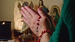 Hands Of Lady Praying Rosary And Statues Of Jesus Mary And Angel