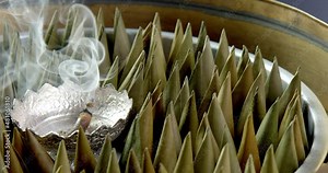 Slow motion – pyramid shape Thai sweet dessert being smoked with scented candle in metal brass steamer to add aroma. Close-up of traditional preparation of Asian cuisine recipe concept.