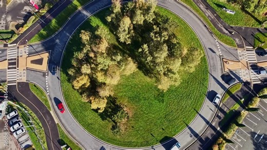 Top down drone view looking directly above circular road intersection with cars driving in Cesson-Sévigné, France. Aerial rising