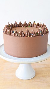 Taking the time to condition your buttercream and using a specific frosting technique can be a game changer. When I’m looking for perfectly smooth buttercream, sharp edges on a cake tier and straight sides- these are the two techniques I rely on. For a single decorated layer cake or 4 tier buttercream cake- these tips will work for you too. Start by conditioning your buttercream to remove air bubbles. Microwave the buttercream in 3-4 second intervals, stirring well after each, until the buttercr
