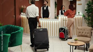 Cheerful smiling concierge personnel helping tourists with accommodation booking. Helpful front desk receptionists answering questions about hotel room amenities during check in process