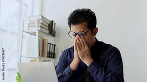 A tired, sleepy, bored businessman from sitting at a desk for a long time and has office syndrome.
