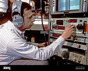 An electrical engineer operates the computer control panel adjusting the video gain and levels of the forward looking infrared radar (FLIR) camera used to record "cold and warm" calibration signals.  The engineer is working in the airborne infrared flying laboratory of the Air Force Geophysics Laboratory (AFGL Stock Photo - Alamy