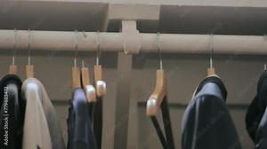 Placing and removing empty hanger from closet. Person grabs a hanger and puts in back from wardrobe