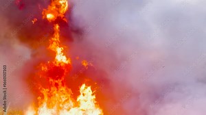 Explosive fire engulfing the wilderness, Firefighters struggling to control flames, Rapid spread of fire worsens damage, Landscapes turning to ash and smoke, Nature suffering from extreme fire