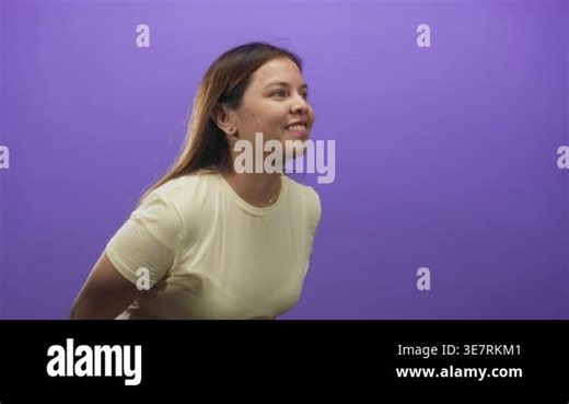 Young woman clapping hands and smiling in purple studio wearing pale yellow shirt and long hair visible; joyful celebration Stock Video Footage - Alamy