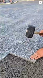 Trowel spreads wet cement over gravel for tiling
