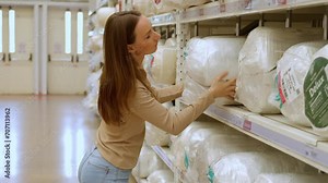 Young beautiful woman choosing pillow at retail furniture store. Housewife pick up the pillow and softness test buying for family