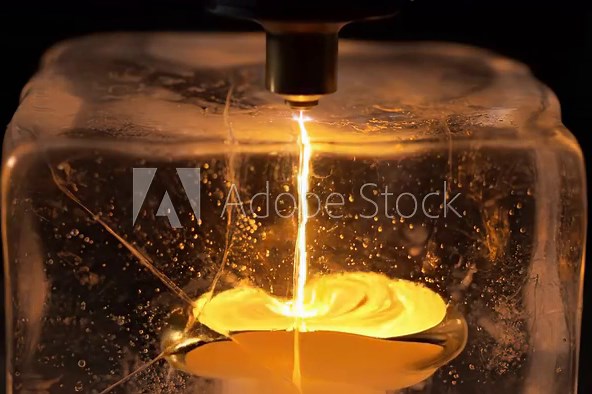 Focused red laser beam generating heat and rapidly melting a large block of ice, demonstrating the powerful energy transfer in a controlled scientific experiment