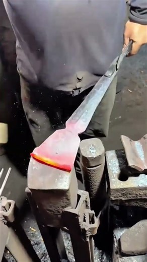 Blacksmith shaping red hot iron on an anvil using a forging hammer