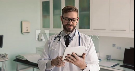 Young doctor working on-line using digital tablet accessing electronic health records, reviewing patient history, lab results, learn x-rays, updating information, consider diagnose and treatment plan
