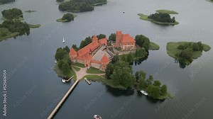 Aerial shot of the Trakai castle surrounded by trees over the Galves lake in Trakai, Lithuania