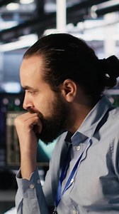 Vertical System administration team collaborating on AI automation deployment in data center. Server farm staff members adjusting machine learning configurations, working together, camera A