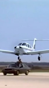 A man adjusts an airplane's landing gear from a moving car, 1985