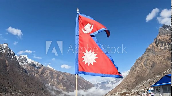 Nepali flag blowing by the wind against the blue sky in Langtang national park, Nepal. The crimson red is Nepal's national color, and it indicates the brave spirits of the Nepalese people.