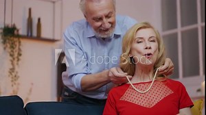 Cheerful senior man presenting pearl necklace to loving wife, birthday present