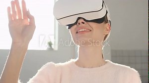 Woman using 3D virtual reality headset. Virtual reality game. Girl with pleasure uses head-mounted display. Woman wearing VR headset in living room
