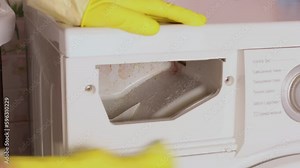 Female hand in household glove rub washing machine drawer of powder container with sponge. Cleaning lady clean container from dirt and coating on walls inside. Dirty house appliances. Home cleaning.