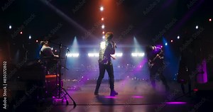 Indie Rock Band Delivers a Mesmerizing Live Performance With Guitars and Drums at a Massive Nightclub. Colorful Lights and Powerful Sound at a Rock Festival. Footage From the Back