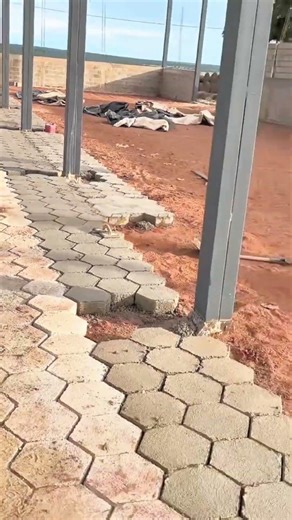 The man is making the shed floor with pre-cast concrete blocks.