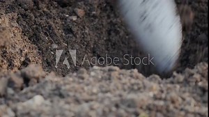 A close-up of a small garden spade as a gardener digs a hole to plant flowers.