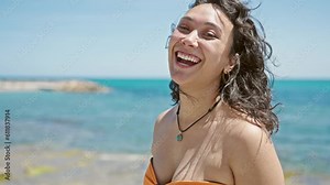 Young beautiful hispanic woman tourist smiling confident wearing bikini at beach