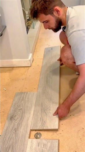 Man installing interlocking vinyl plank flooring during home renovation