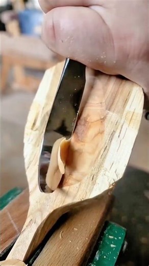 Hand carving the smooth deep bowl of a wooden cooking spoon using a specialized curved knife