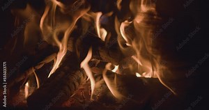 Charred fire logs with glowing embers and hot dancing flames in campfire burner