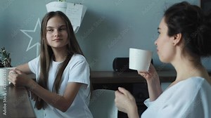 mother and teenage daughter drink tea in the kitchen