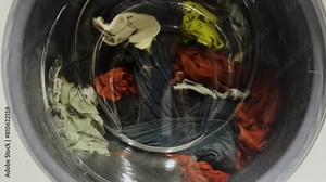 The process of washing things in a washing machine. Clothes are washed in a washing machine. Clothes spinning in the washing machine.