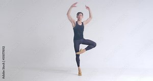 Young male ballet dancer performs pirouette and acrobatic elements in ballet dance, white background.