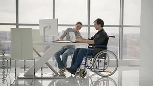 Colleagues, woman shows to man in wheelchair pie chart on paper document work together in office. Workers discuss collect data sit at desk. Usual life of people with physical disability concept.