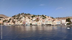 Rhodes, Greece: Pan shot of Symi Island a Greek island, part of the Dodecanese island group and ships docked in it's harbor at Symi Town, surrounded by colorful neoclassical houses