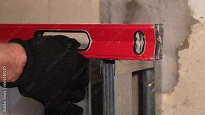 Restoration with bubble level indoors. Man is holding a spirit level in hands. Maintenance repair works renovation in the flat.