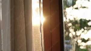 Slow motion of the curtains on the window There was morning light streaming through the bedroom window. Look out over the mountains and trees as the sun rises.
