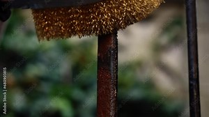 Homeowner cleaning rusty wrought iron fence with wire brush