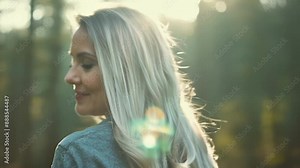 A woman with long flowing grey hair takes a peaceful walk through a forest radiating natural confidence.
