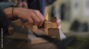 Two young adult hands solving a interlocking wooden puzzle game.