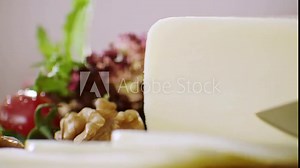 Process of cutting the cheddar cheese on a cutting board close-up, slow motion. Knife Cutting Slices Of Turkish Kasar Cheese