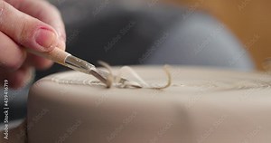Close-up of shaping process of workpiece with a tool in a pottery studio. Clay shavings. Slow motion