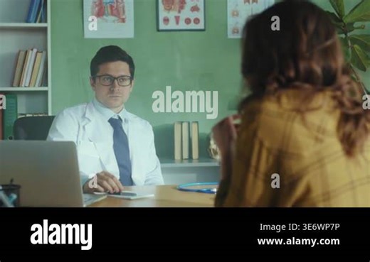 male doctor listening to female patient revealing concerns, patient turned away in mustard jacket, clinician maintains Stock Video Footage - Alamy