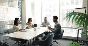 Four multi-ethnic workmates take part in briefing or seminar event, share opinion, vision, gathered together in modern conference room for decision-making, strategy planning and business communication