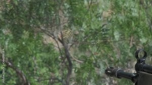 Close-up of the barrel of a G3 Assault rifle as it's being fired outdoors in a wooded area.