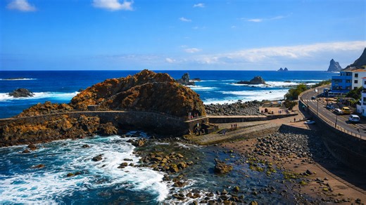 A scenic coastal road curving around rugged ocean rocks