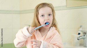 Happy smiling little girl brush teeth using ultrasonic electric toothbrush in bathroom at home. Oral hygiene, dental and gum health, healthy teeth. Daily life and routine.