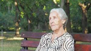 Face of an elderly person close-up. An elderly woman in a park on a bench.