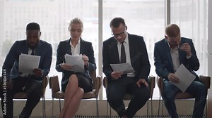 Diverse applicants waiting for job interview sitting in line and reading cv. Realtime