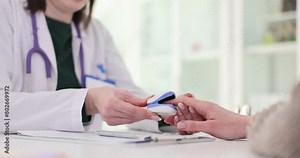 Doctor and patient measure pulse using pulse oximeter. Medical device for measurement of blood oxygen saturation level