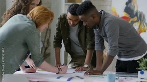 Medium tilting shot of four multiethnic creative designers in their twenties, standing around table and drawing flowchart of new design project, proposing colour combinations for different parts